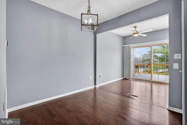 a front view of a building with large trees and plants