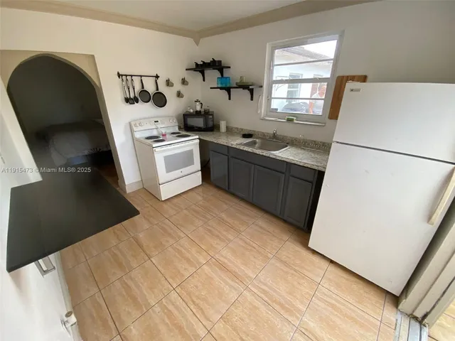 a kitchen with stainless steel appliances a stove a refrigerator a sink a dining table and chairs