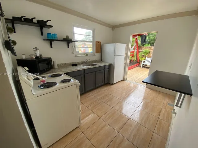 a kitchen with stainless steel appliances a stove a sink a refrigerator white cabinets and wooden floor