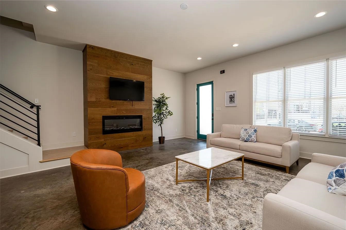 752 Meda Street Memphis, TN 38104 - Photo 5 of 18 Living space featuring a wood-paneled accent wall with an integrated electric fireplace, multiple recessed lights, and large windows with blinds