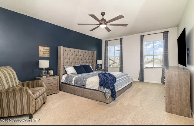 a bedroom with a large bed couch and windows