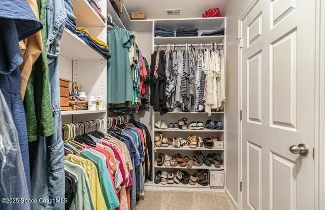 a view of walk in closet with clothes and shoes