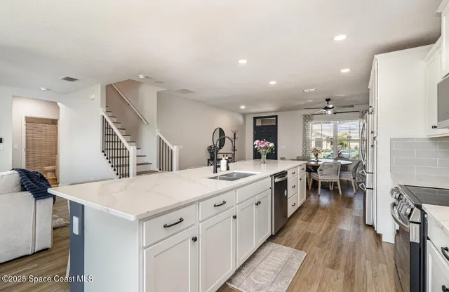 a large kitchen with kitchen island a sink dishwasher a dining table and chairs with wooden floor