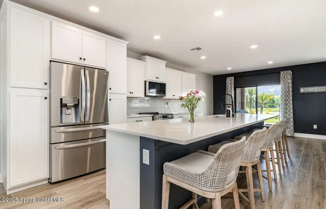 a kitchen with stainless steel appliances granite countertop a refrigerator a sink dishwasher a stove and a refrigerator with wooden floor