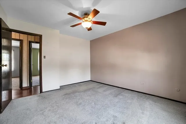 an empty room with chandelier fan and windows