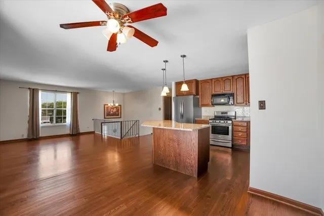 a kitchen with stainless steel appliances kitchen island hardwood floor and a window