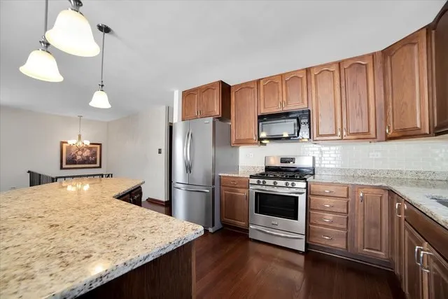 a kitchen with stainless steel appliances granite countertop a stove a sink and a refrigerator