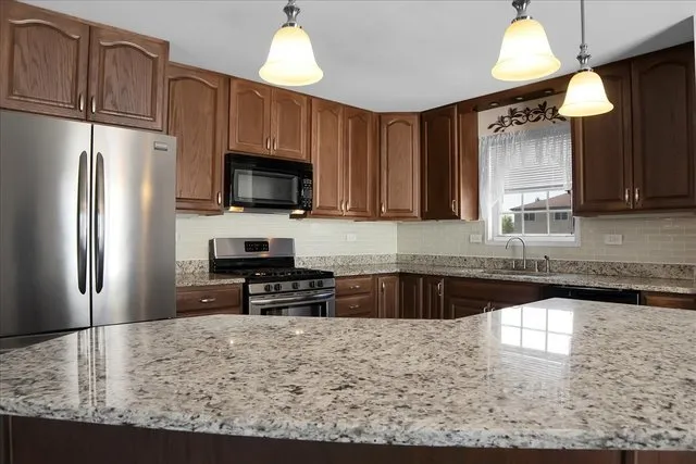 a kitchen with granite countertop a refrigerator stove top oven a sink and dishwasher