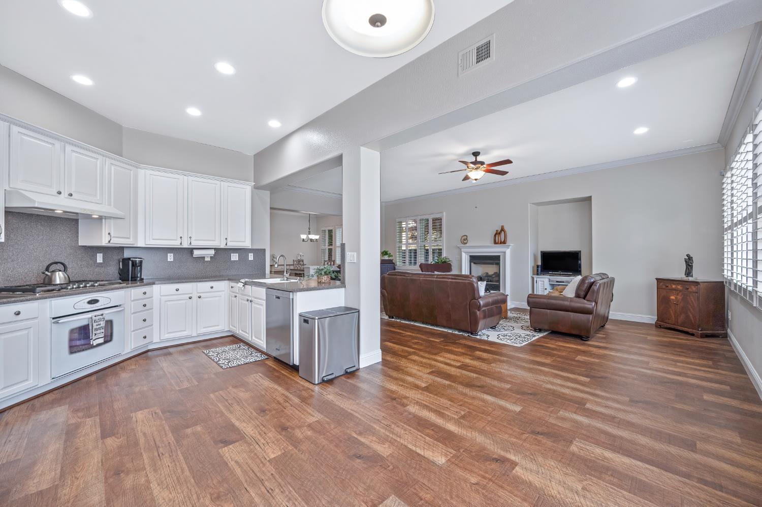 5966 Tanus Circle Rocklin, CA 95677 - Photo 18 of 38 a large white kitchen with a stove a sink dishwasher and a fireplace with wooden floor