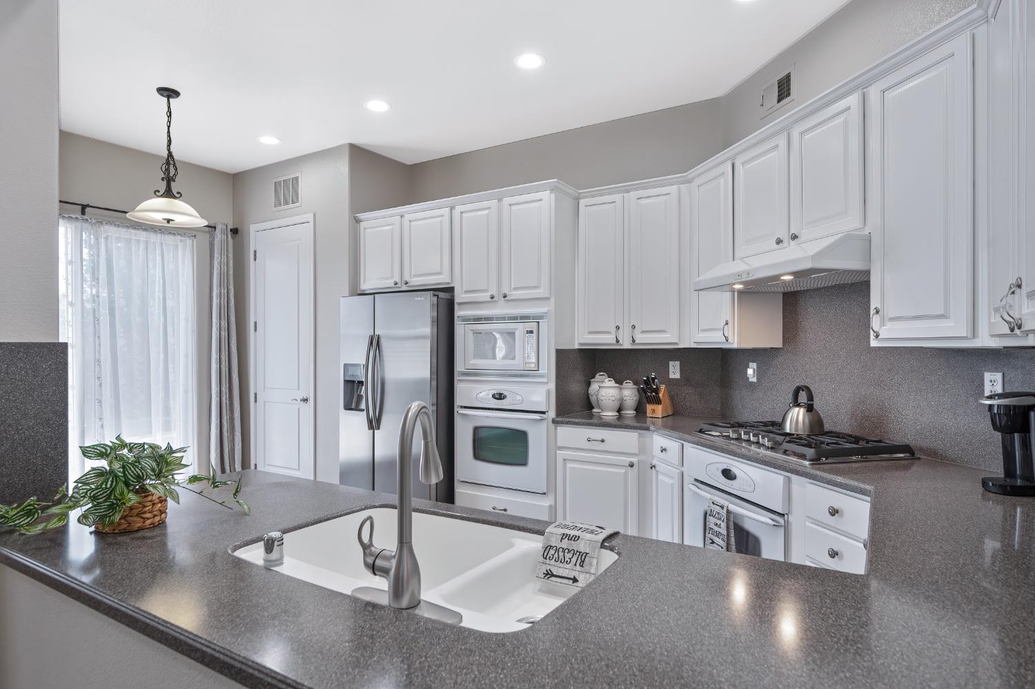 5966 Tanus Circle Rocklin, CA 95677 - Photo 20 of 38 a kitchen with stainless steel appliances a sink a stove and a counter top space