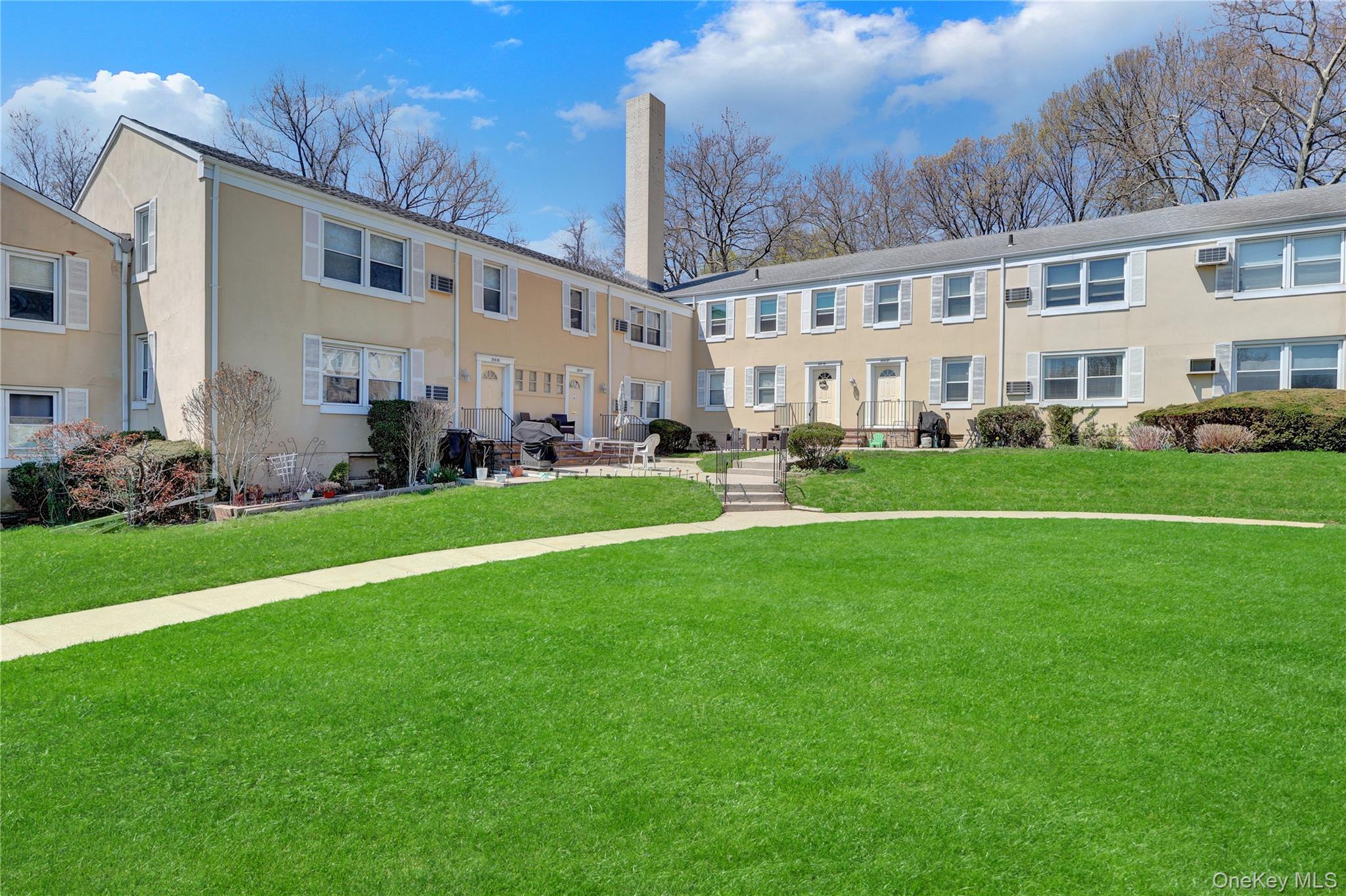 251-21 71st Road, Unit 44A Queens, NY 11426 - Photo 2 of 25 a view of a big building with a big yard and plants