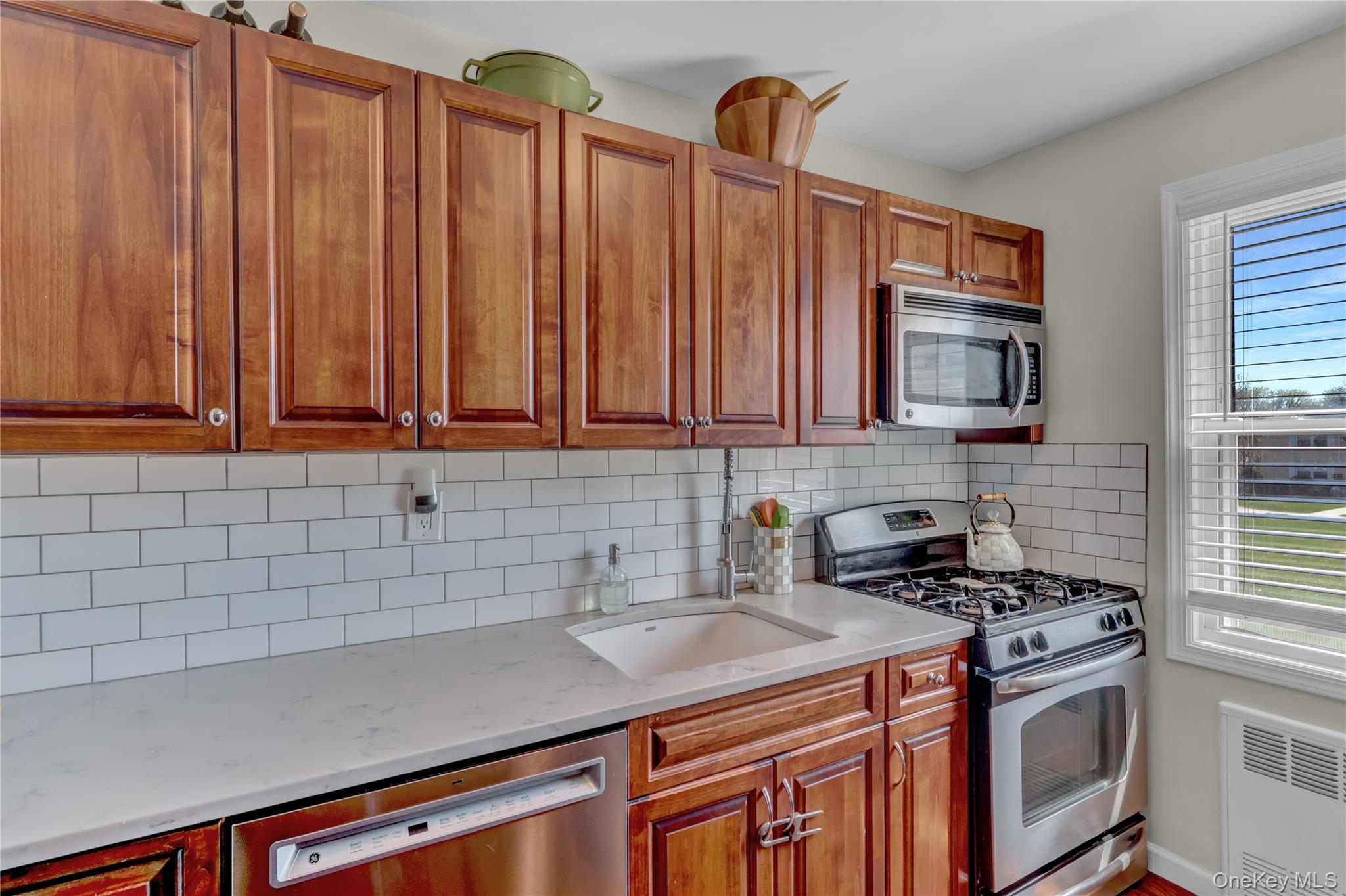 251-21 71st Road, Unit 44A Queens, NY 11426 - Photo 3 of 25 a kitchen with stainless steel appliances a stove a sink and a microwave