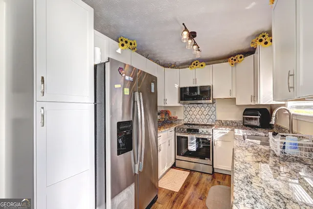 a kitchen with granite countertop a refrigerator stove and microwave