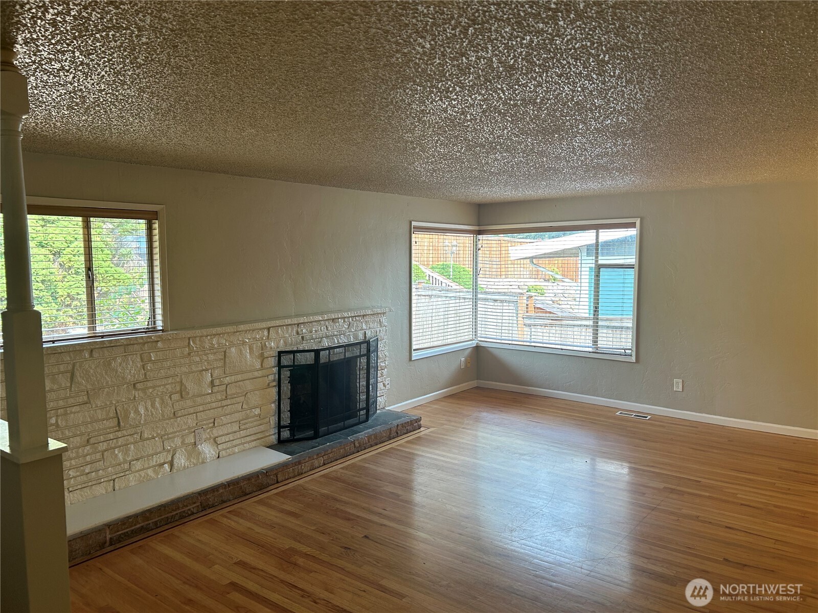 6605 South 127th Place Seattle, WA 98178 - Photo 4 of 38 an empty room with wooden floor fireplace and windows