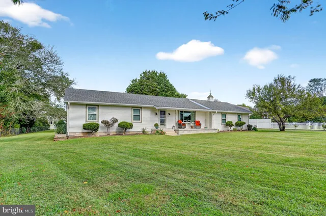 a front view of a house with a garden and trees
