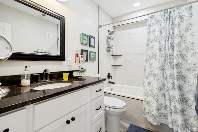 332 South 500 West Payson, UT 84651 - Photo 24 of 50 Bathroom featuring a dark granite-style countertop, undermount sink, white cabinetry with dark hardware, a framed mirror, and a white tiled shower-tub combination