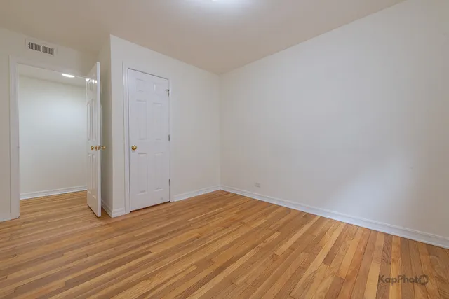 a view of empty room with wooden floor and entryway