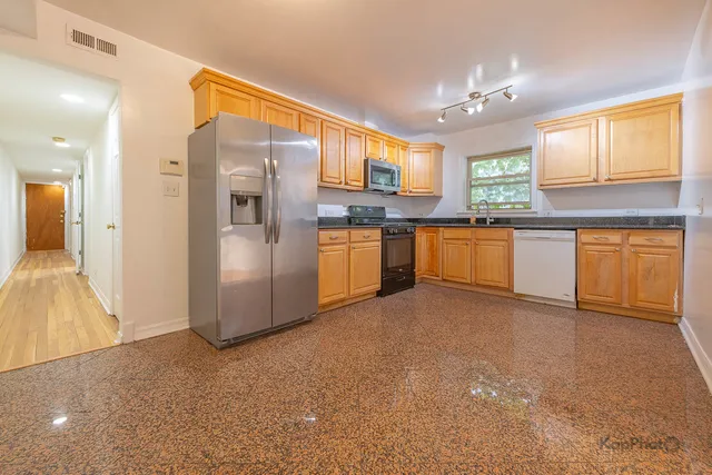 a kitchen with stainless steel appliances granite countertop a refrigerator a sink dishwasher a oven with white cabinets and wooden floor