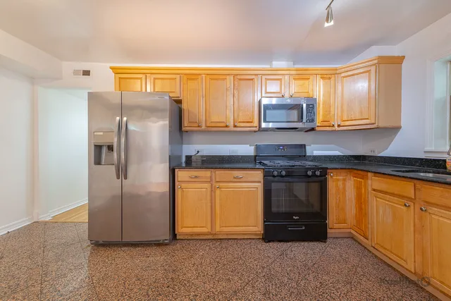 a kitchen with stainless steel appliances granite countertop a refrigerator and a sink