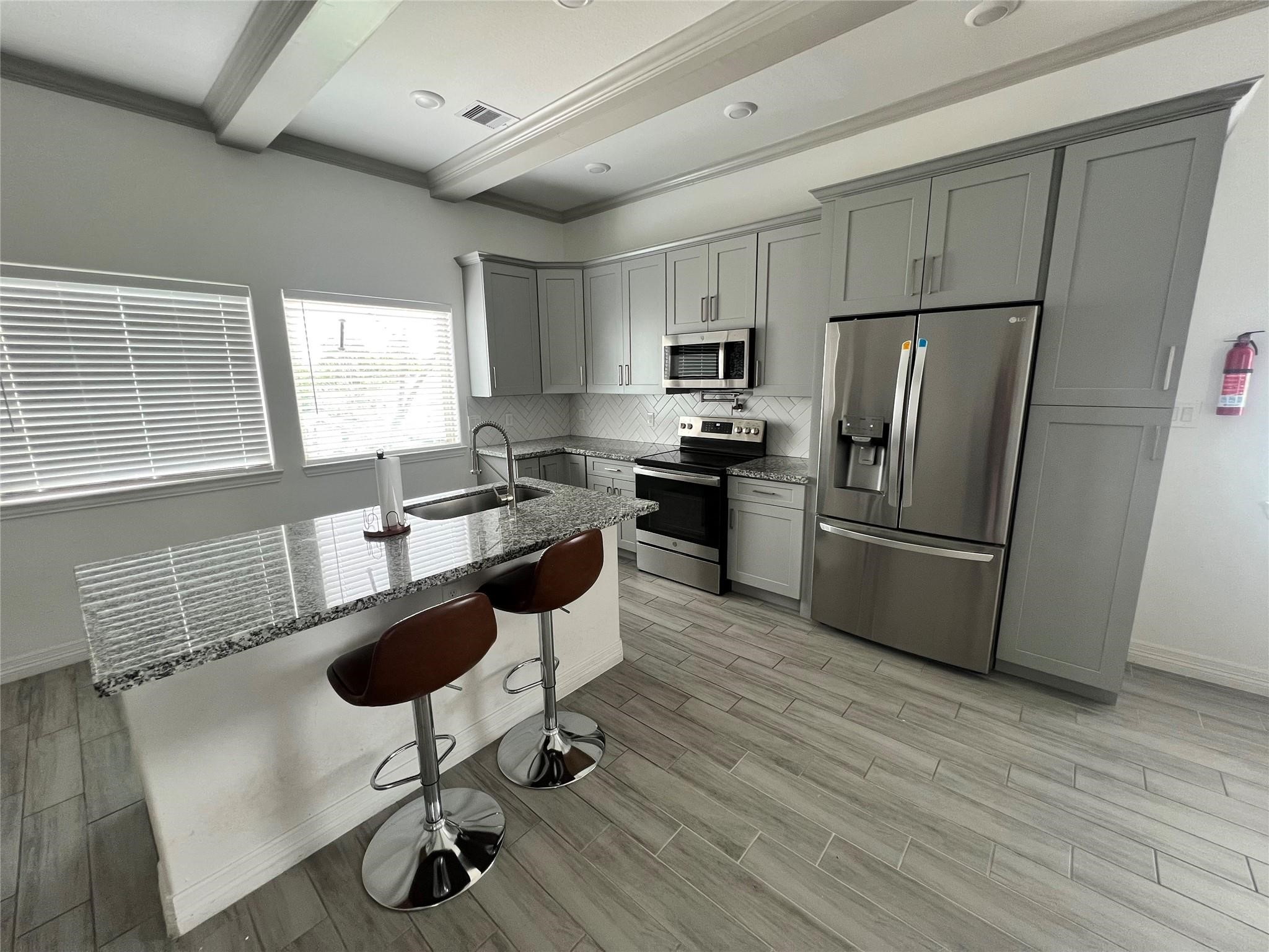 3407 Sakowitz Street, Unit B Houston, TX 77026 - Photo 20 of 23 a kitchen with kitchen island stainless steel appliances a sink a stove a refrigerator cabinets and dining table