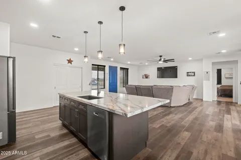 a large kitchen with stainless steel appliances kitchen island a large counter top and a wooden floors