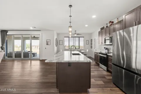 a large kitchen with stainless steel appliances granite countertop a refrigerator a oven and a stove with wooden floor