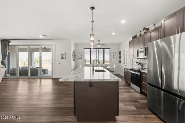 a large kitchen with stainless steel appliances granite countertop a refrigerator a oven and a stove with wooden floor