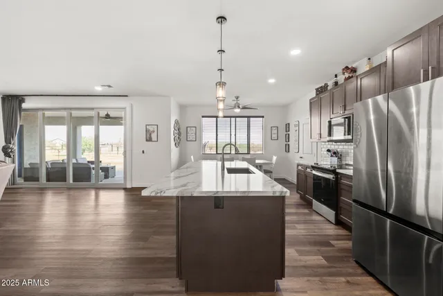 a large kitchen with stainless steel appliances granite countertop a refrigerator a oven and a stove with wooden floor