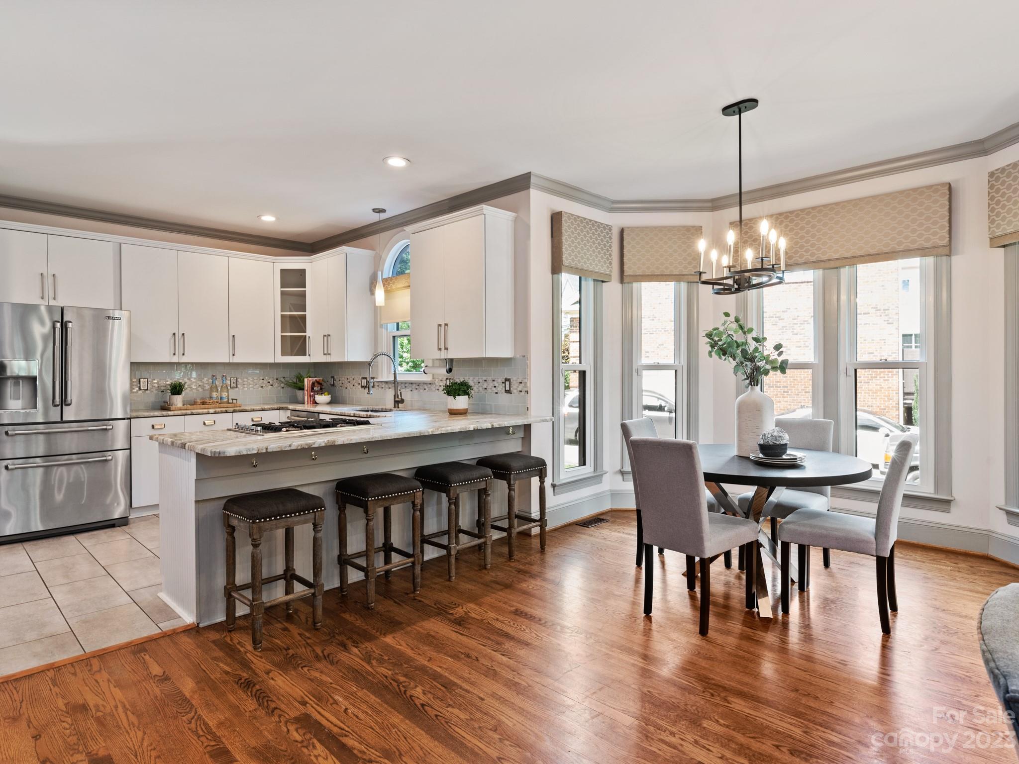 684 Beacon Knoll Lane Fort Mill, SC 29708 - Photo 17 of 46 a kitchen with stainless steel appliances granite countertop a stove top oven a refrigerator a dining table and chairs with wooden floor