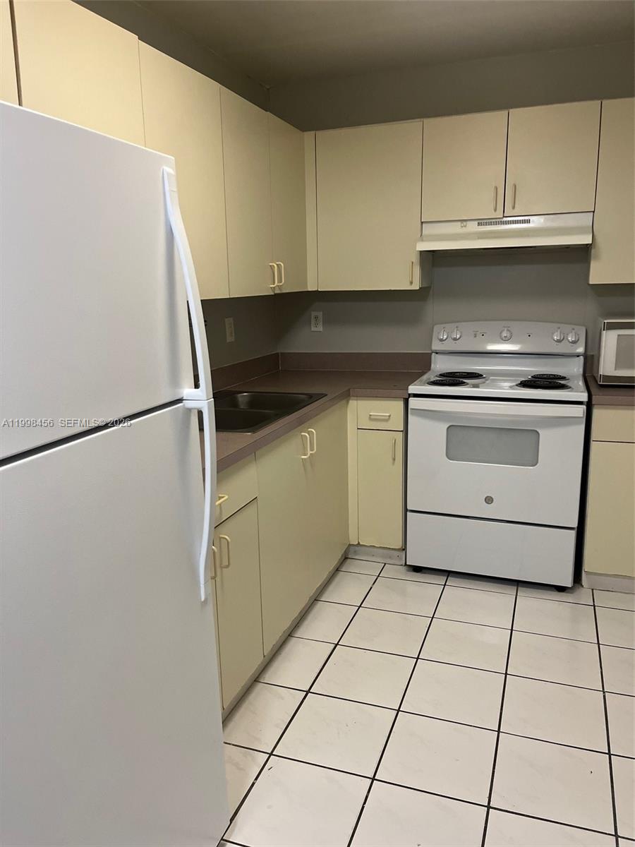 5625 West 20th Avenue, Unit 306 Hialeah, FL 33012 - Photo 3 of 9 a kitchen with a white cabinets and white appliances