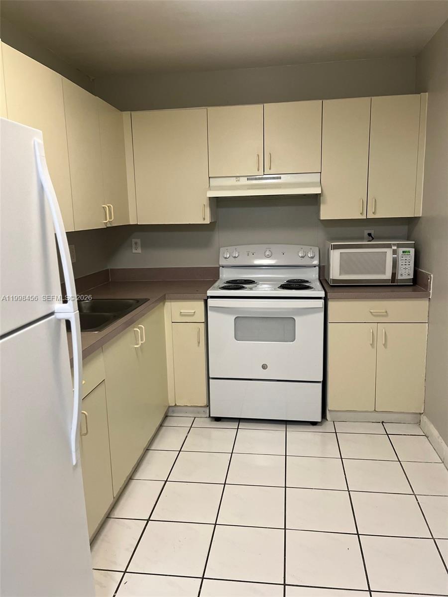5625 West 20th Avenue, Unit 306 Hialeah, FL 33012 - Photo 4 of 9 a kitchen with granite countertop a stove a sink and a refrigerator