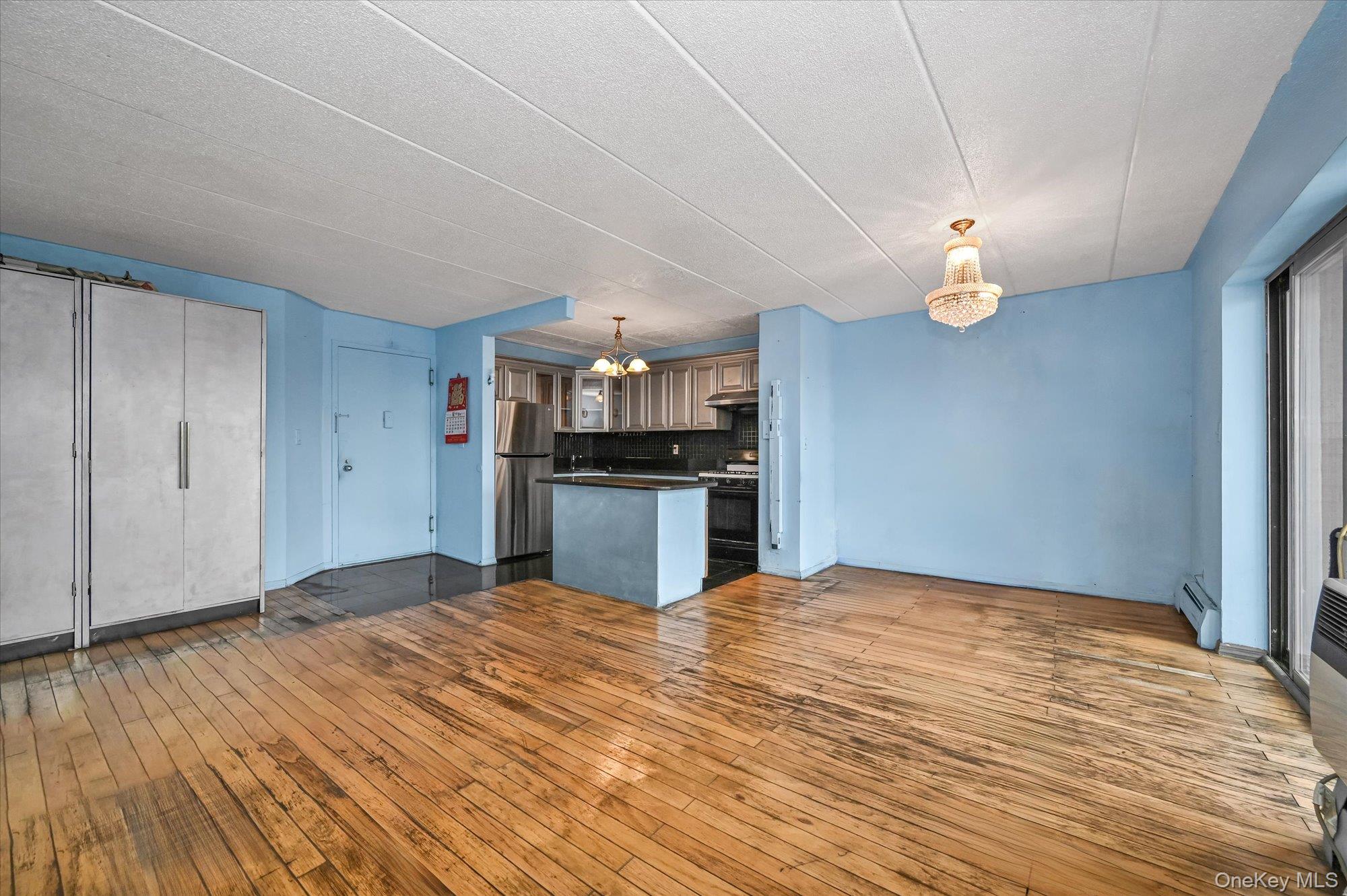 136-75 37th Avenue, Unit PH B Queens, NY 11354 - Photo 16 of 17 a view of kitchen and empty room with wooden floor