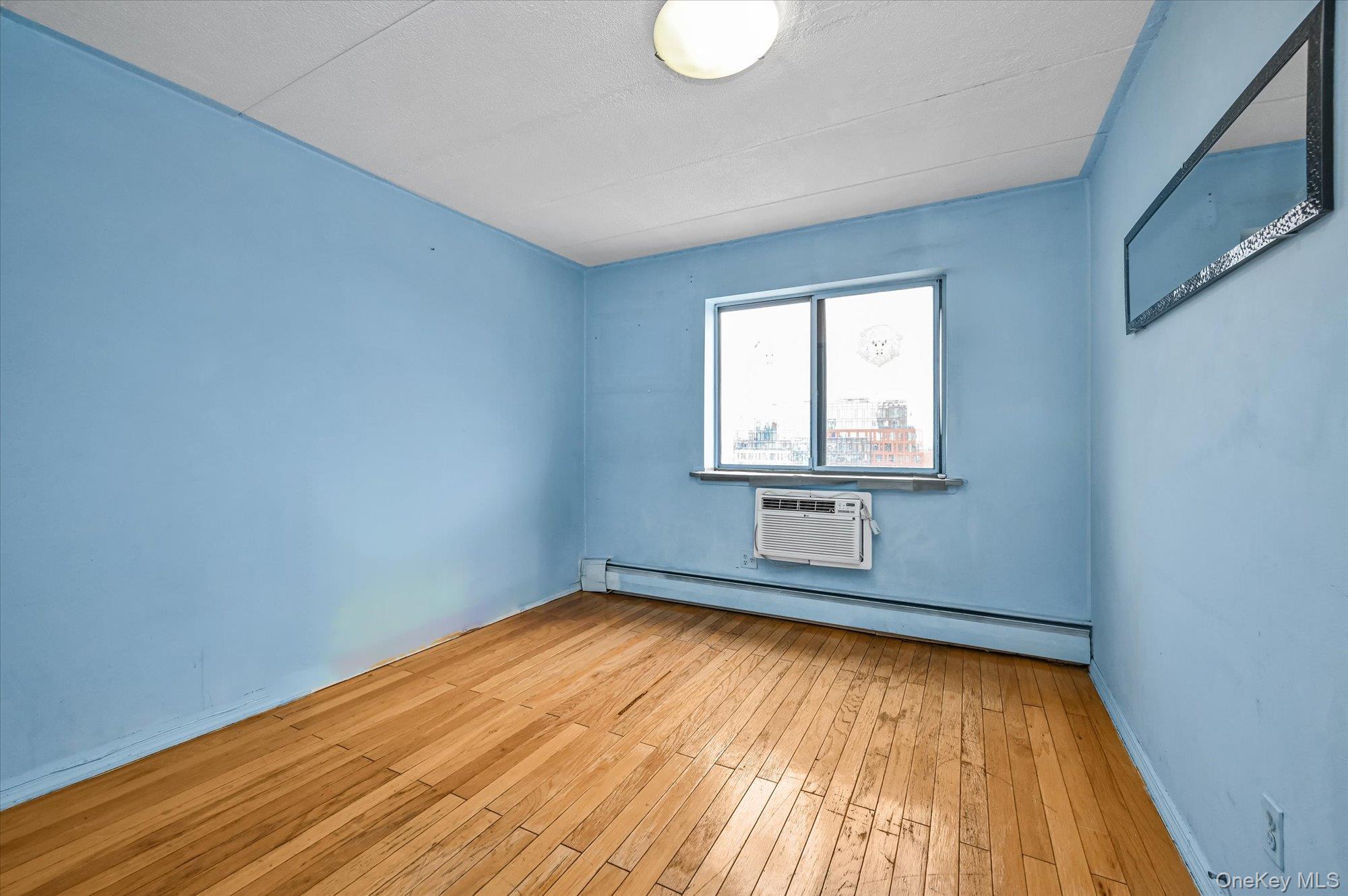 136-75 37th Avenue, Unit PH B Queens, NY 11354 - Photo 8 of 17 a view of empty room with wooden floor and fan