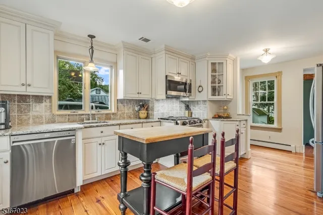 a kitchen with stainless steel appliances granite countertop a stove top oven a sink a stove a dining table and chairs