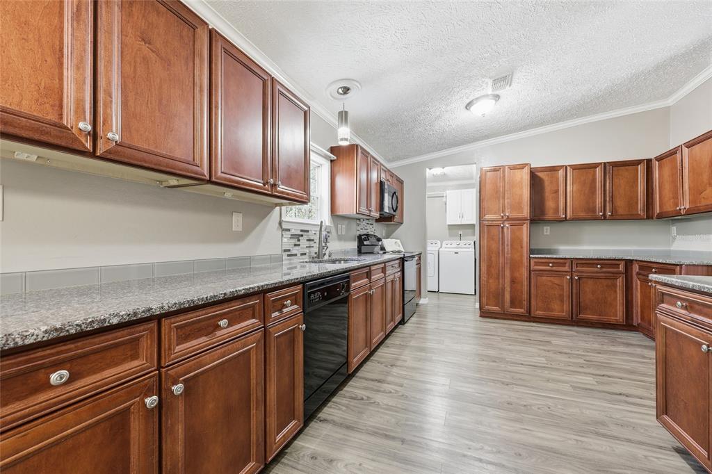 269 Southwest Backwoods Glen Fort White, FL 32038 - Photo 6 of 31 a kitchen with stainless steel appliances granite countertop wooden cabinets a stove a sink and dishwasher with wooden floor