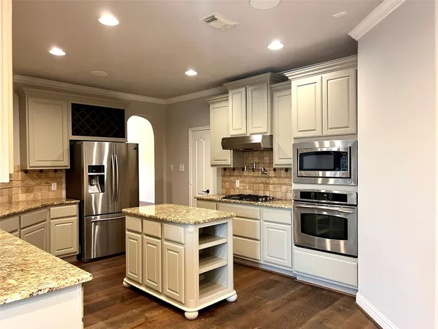 a kitchen with stainless steel appliances kitchen island granite countertop a refrigerator and a stove top oven