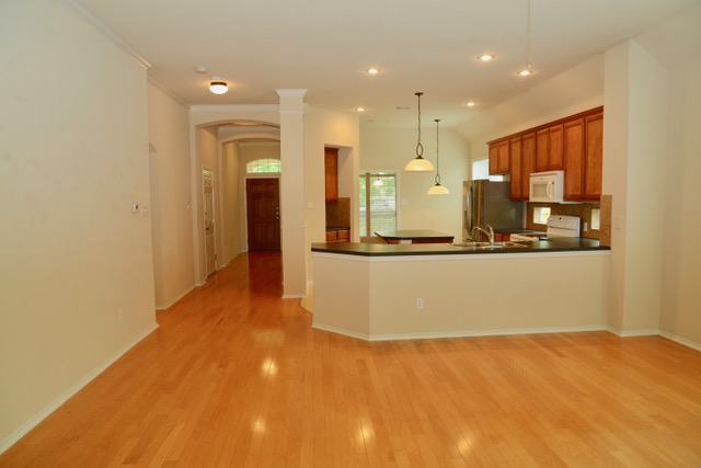 138 Chestnut Court Georgetown, TX 78633 - Photo 18 of 25 Hardwood floors stretch across this open-concept layout, connecting the kitchen to the entry hall.