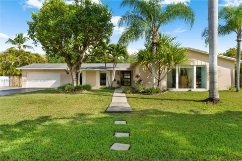 a front view of a house with a yard and palm trees