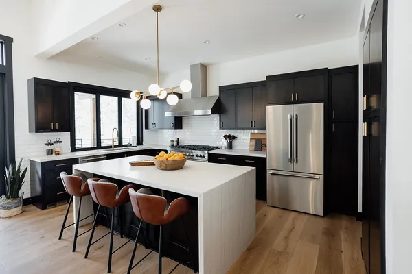 a kitchen with stainless steel appliances a dining table chairs refrigerator and microwave