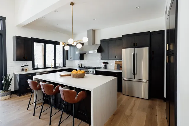 a kitchen with stainless steel appliances a dining table chairs refrigerator and microwave