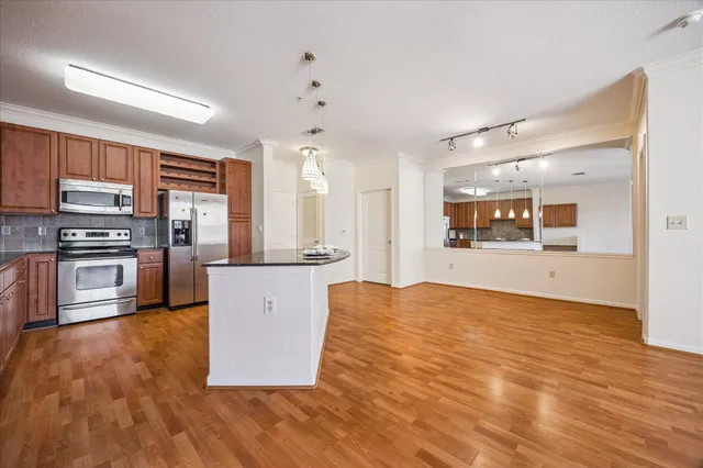 a large kitchen with stainless steel appliances kitchen island granite countertop a stove and a refrigerator