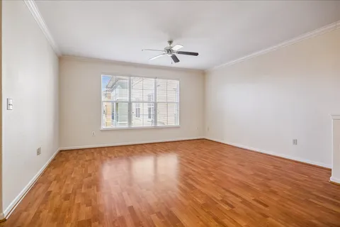 an empty room with wooden floor chandelier fan and windows