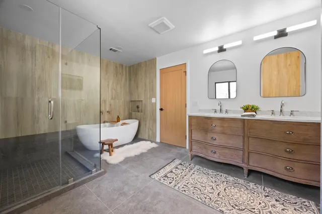 a spacious bathroom with a granite countertop tub sink a mirror and shower