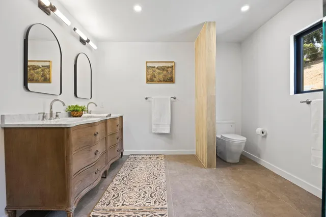 a spacious bathroom with a double vanity sink toilet and a window