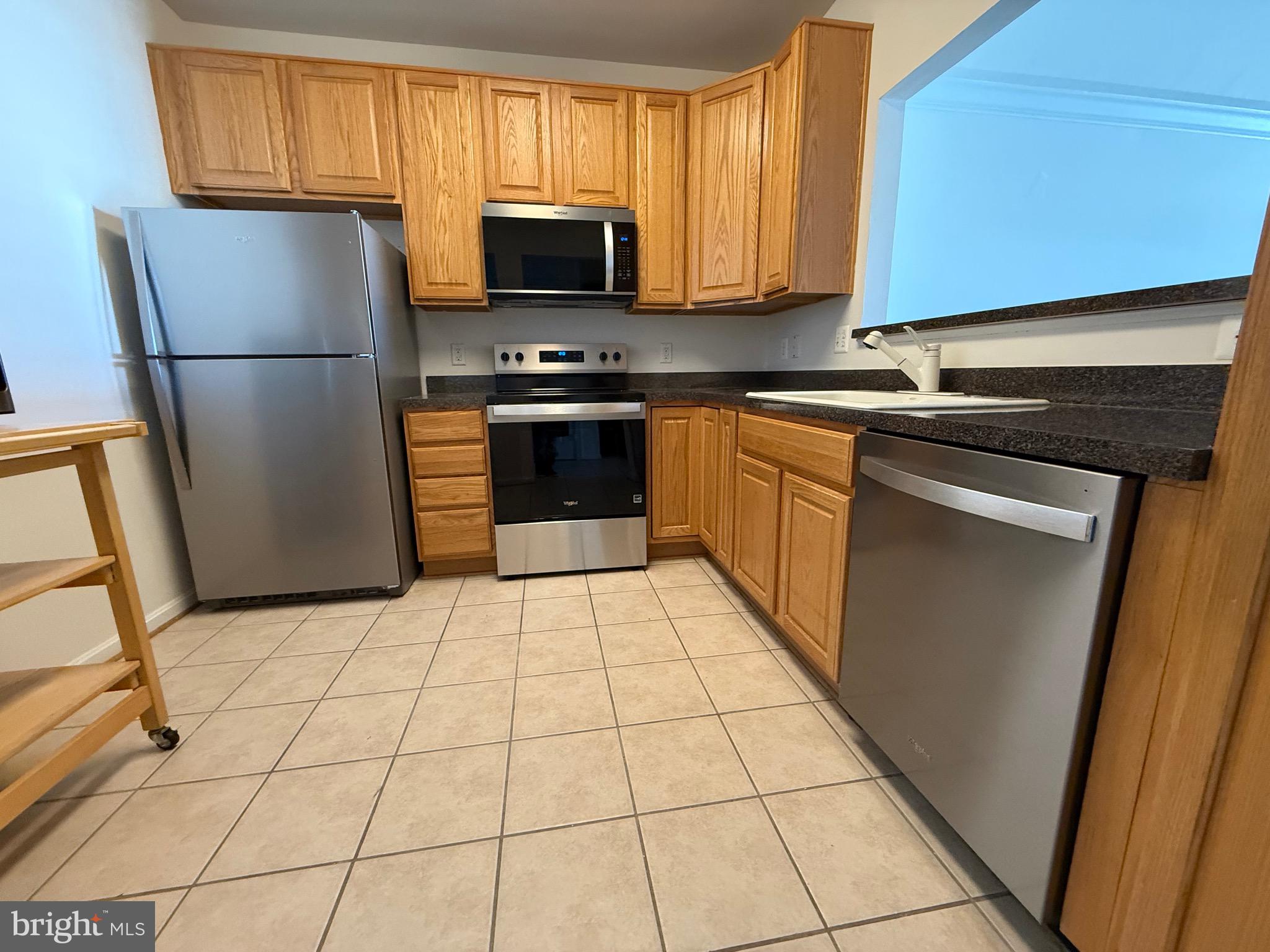 8615 Wandering Fox Trail, Unit 208 Odenton, MD 21113 - Photo 1 of 28 a kitchen with stainless steel appliances a refrigerator sink and microwave