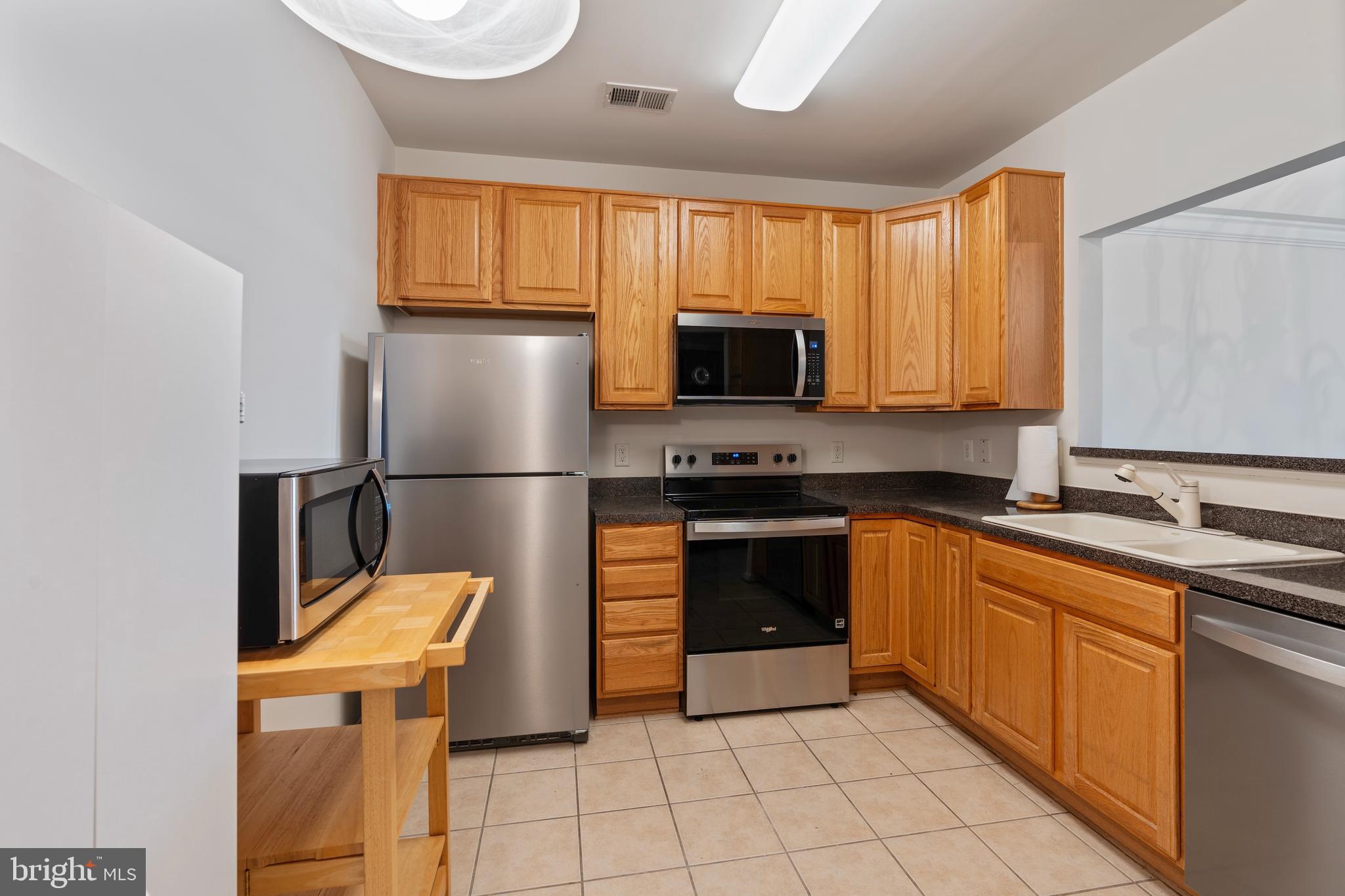 8615 Wandering Fox Trail, Unit 208 Odenton, MD 21113 - Photo 5 of 22 a kitchen with stainless steel appliances granite countertop a refrigerator sink and cabinets