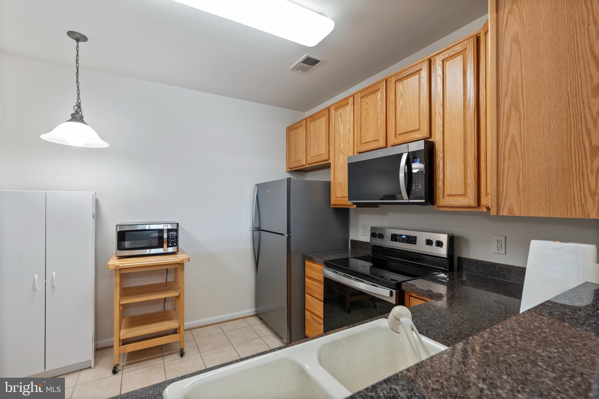 8615 Wandering Fox Trail, Unit 208 Odenton, MD 21113 - Photo 6 of 22 a kitchen with stainless steel appliances a stove a refrigerator and cabinets