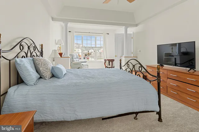 a bedroom with a bed and a flat tv screen on dresser