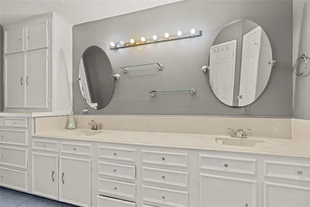 a bathroom with double vanity white cabinets and a mirror