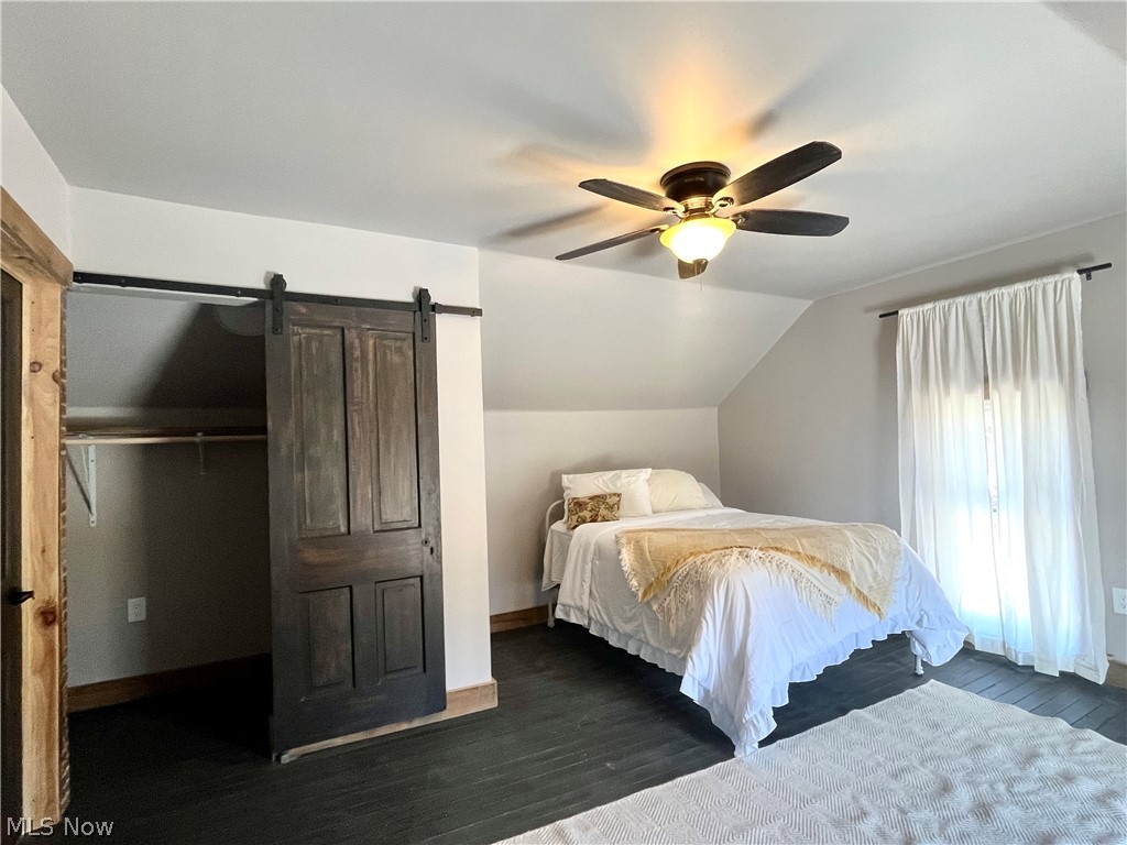 12972 Gilmore Road Southeast Port Washington, OH 43837 - Photo 33 of 50 Bedroom featuring a barn door, dark wood finished floors, vaulted ceiling, and a ceiling fan